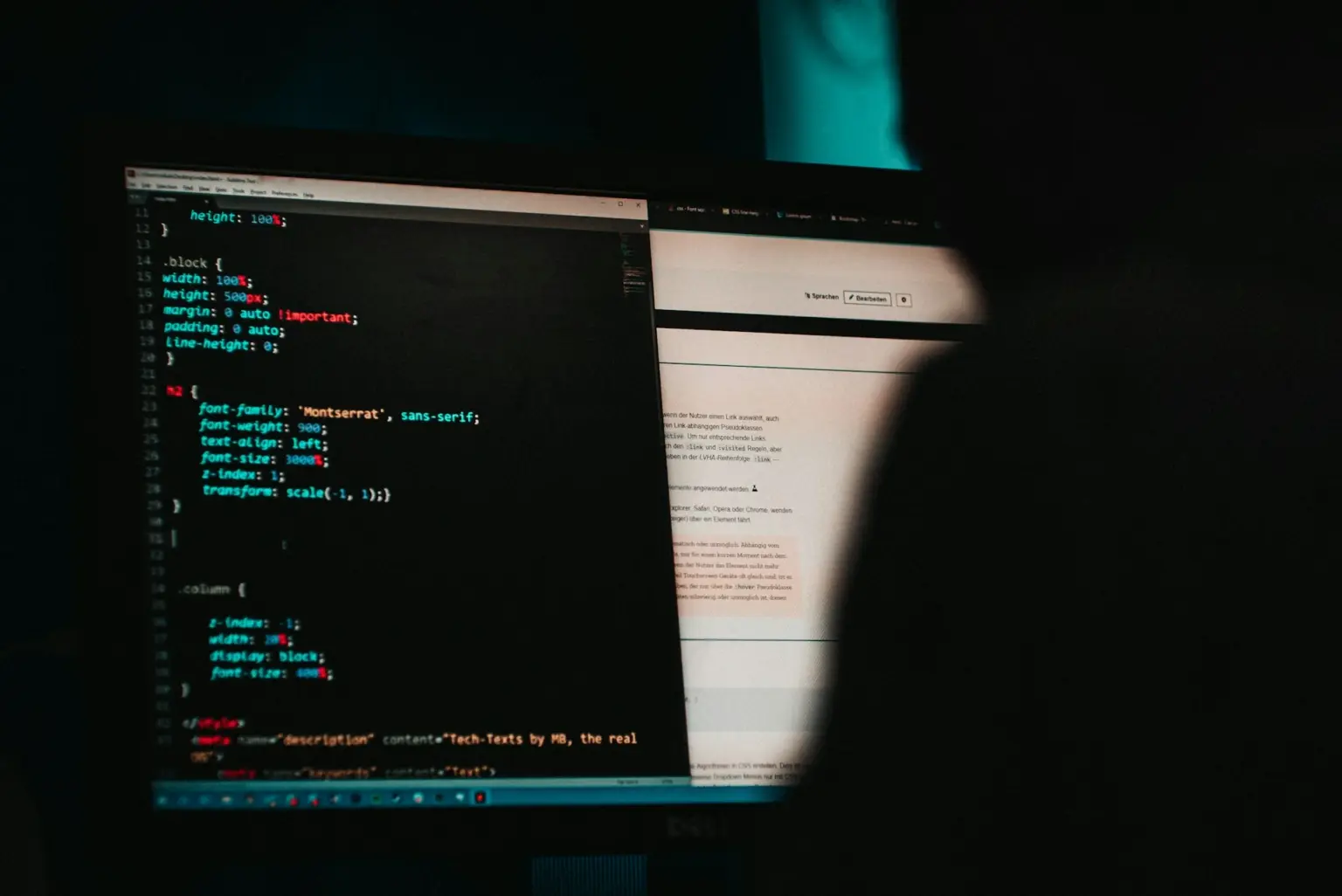 Software code and a browser window displayed on dark computer monitors